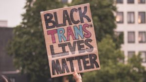 Black Trans Lives Matter is written on a cardboard sign
