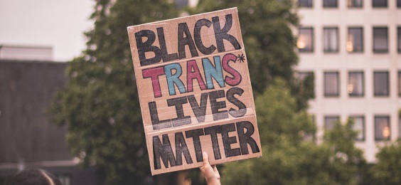 Black Trans Lives Matter is written on a cardboard sign