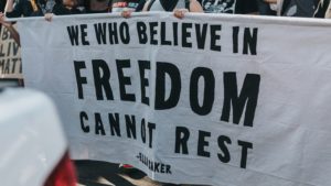 Protestors carry a banner reading "We who believe in freedom cannot rest" - Ella Baker